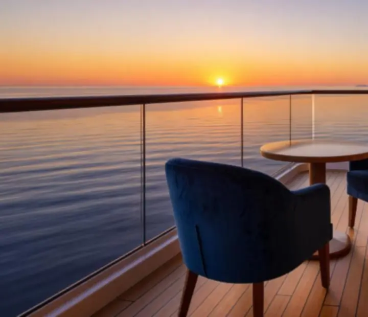 Private cruise balcony overlooking a calm evening ocean horizon